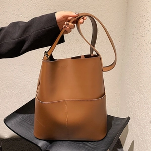 Nahaufnahme einer braunen Leder-Eimertasche mit Tragegriff und feinen Nähten im Detail