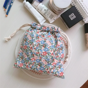 Macro shot of cotton drawstring floral storage bag with cosmetics on a white table