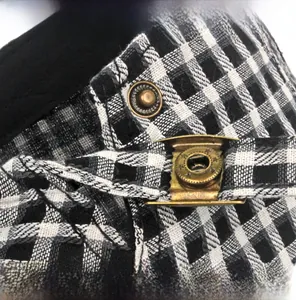 Detail view of the adjustable stainless steel buckle on black and white plaid beret cap