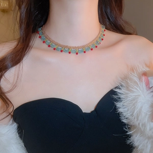 Detailed close-up of red and teal beaded choker with golden fan-shaped patterns