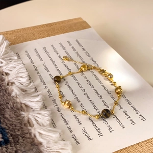 Detail of 18K gold-plated beaded bracelet with tiger eye stones on vintage book