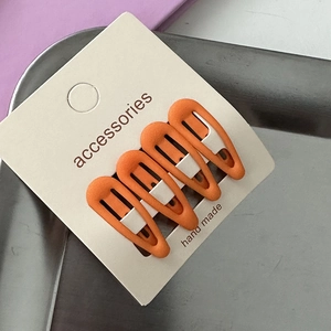 Close-up of four orange star-shaped hair clips on a beige card for little girls