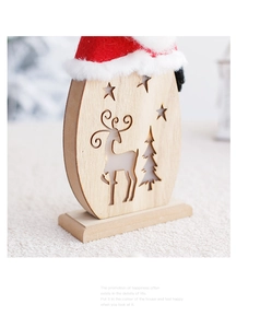Detail of wooden Christmas ornament with reindeer cutout and red fabric hat for holiday decor