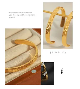 Dettaglio del bracciale rigido dorato martellato irregolare con texture in una scatola