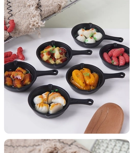 Detailed macro view of miniature resin pan food charms with dumplings and sausage