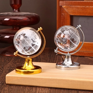 Close-up of two mini crystal globes with gold and silver metal stands on a wooden desk