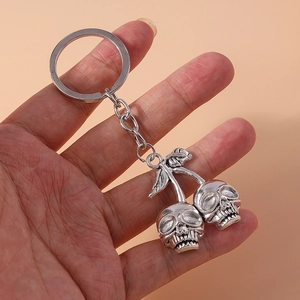 Gothic skull cherry keychain in vintage silver finish held against beige background