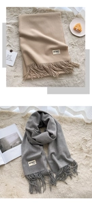 Detail of soft cashmere-like scarves in beige and grey with elegant fringe and logo tags