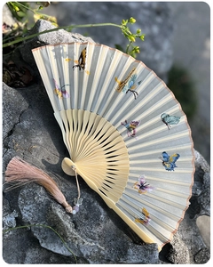 Detail of hand-embroidered butterflies on silk folding fan with pink tassel and bamboo ribs