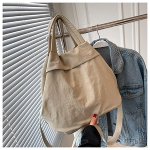 Close-up of beige nylon crossbody bag with pleated texture and wide shoulder strap