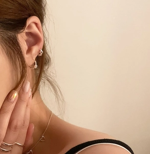 Close-up of minimalist sterling silver earrings and heart necklace worn by a model