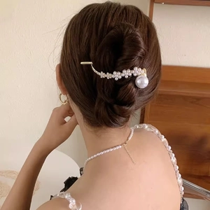 Elegant gold metal hair claw with pearl flower accents and pendant on woman's updo hair