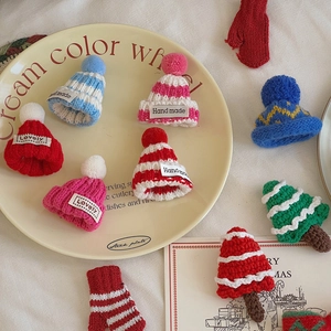 Miniature knitted Christmas hats in assorted colors on a beige decorative ceramic tray