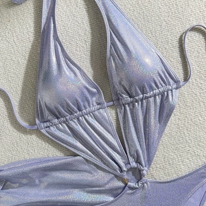 Détail d'un monokini violet holographique avec anneau doré et tissu plissé
