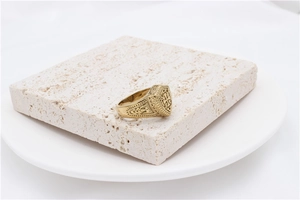 Detailed view of vintage gold cross signet ring displayed on a textured stone stand