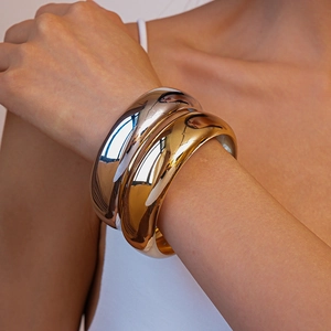 Close-up of chunky gold and silver bangles with a high-polished mirror finish on wrist