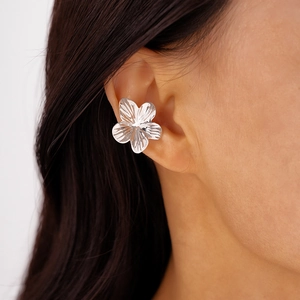 Close-up of silver floral ear clip on model showing detailed metallic texture and shine