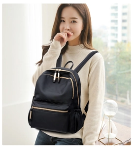Classic black nylon backpack detail featuring shiny finish and polished gold metal zippers