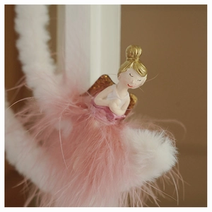 Close-up of a pink angel ornament with soft feathers and star details for Christmas tree