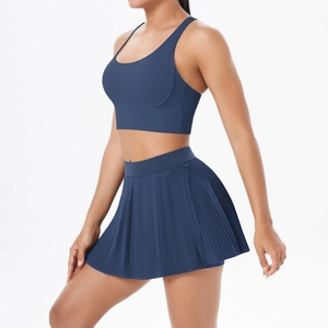 Detail of navy blue athletic set featuring high-waisted pleated skirt and racerback vest