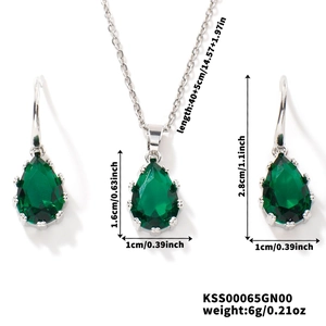 Detailed view of silver necklace and earrings set with green pear-cut gemstones