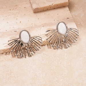 Detail view of silver geometric flower stud earrings with white oval stone on stone background