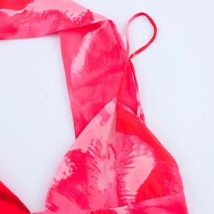 Detail eines Kleides mit rosa Blumenmuster, dünnen Trägern und seidiger Chiffon-Textur
