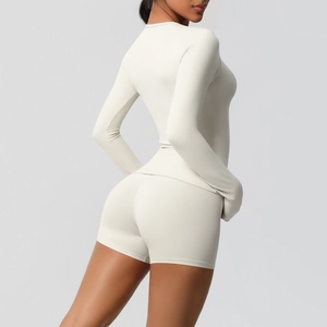 Detail view of cream long sleeve yoga top and high-waisted shorts with seamless texture