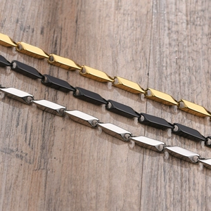 Detailed view of gold, black and silver titanium steel geometric link chains on wood