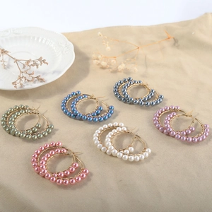 Detail view of multi-color natural mother-of-pearl beaded hoop earrings in gold finish