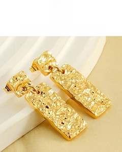 Detail of 18K gold plated earrings with vintage wrinkled texture on silk background