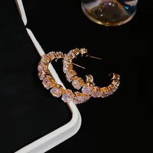 Golden C-shaped hoop earrings with sparkling clear cubic zirconia in a pave setting