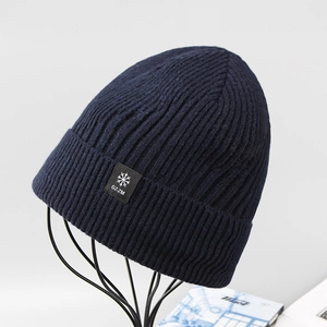 Dettaglio del berretto invernale a maglia a coste blu navy con logo a fiocco di neve sul bordo
