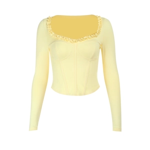 Close-up of pale yellow long sleeve top with ruffle neckline and corset-style stitching