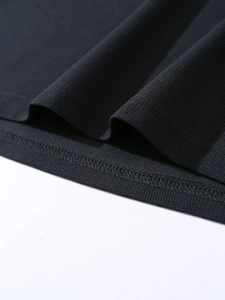 Macro detail of black pique knit fabric showing refined texture and double-stitch hem