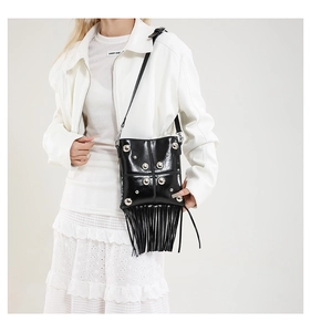 Detail of black fringe crossbody bag with silver studs and polished leather texture