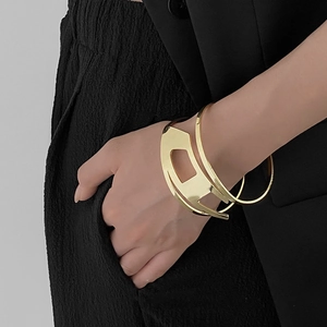 Detail of a minimalist gold layered geometric open cuff bracelet on a female model arm