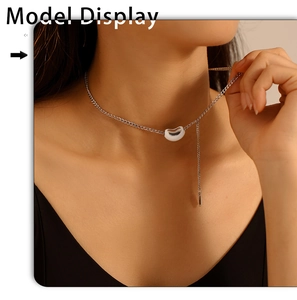Close-up of minimalist bean pendant necklace with silver chain on model neck