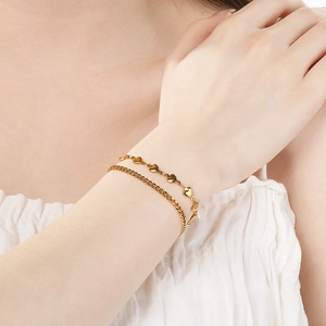 Close-up of gold stainless steel double-layer bracelet with heart charms on model