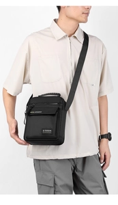 Detail of black nylon shoulder bag with adjustable strap and multiple zipper pockets