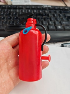 Close-up of a red mini fire extinguisher water gun toy with black handle and blue nozzle