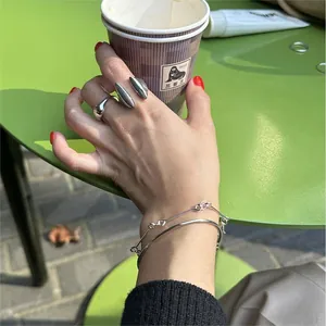 Close-up of minimalist S925 sterling silver geometric open bangle and rings on hand