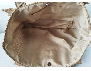 Detail view of woven straw tote bag featuring khaki fabric lining and magnetic snap closure