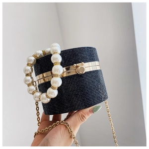 Detailed shot of black cylindrical evening bag with rhinestones and pearl handle