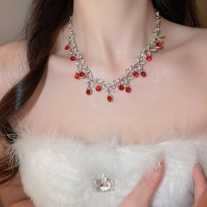 Close-up of elegant silver necklace with red drop gemstone worn by a model in soft lighting