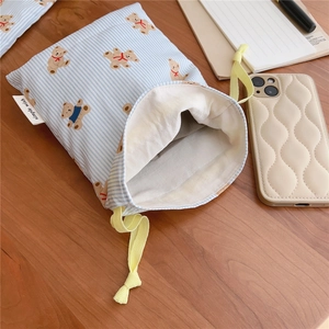Close-up of blue striped cotton storage bag featuring bear prints and yellow drawstring
