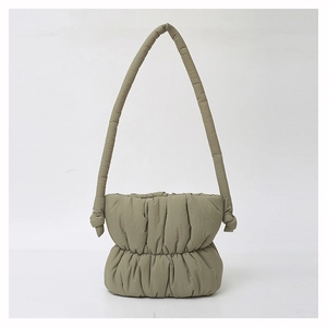 Detail of green puffy nylon bucket bag showing soft quilted texture and knotted strap design