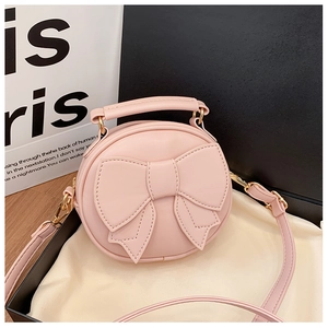 Detailed close-up of pink round kid purse with large bow and golden metal hardware