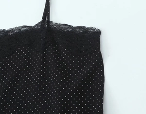 Detail van zwarte top met polkadots, delicate kant en dunne schouderbandjes