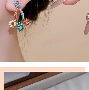 Close-up of elegant floral earrings with multi-colored zircons worn on model ear